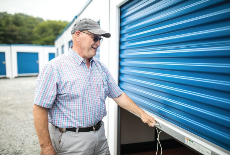 a man in a plaid shirt is opening a blue storage door