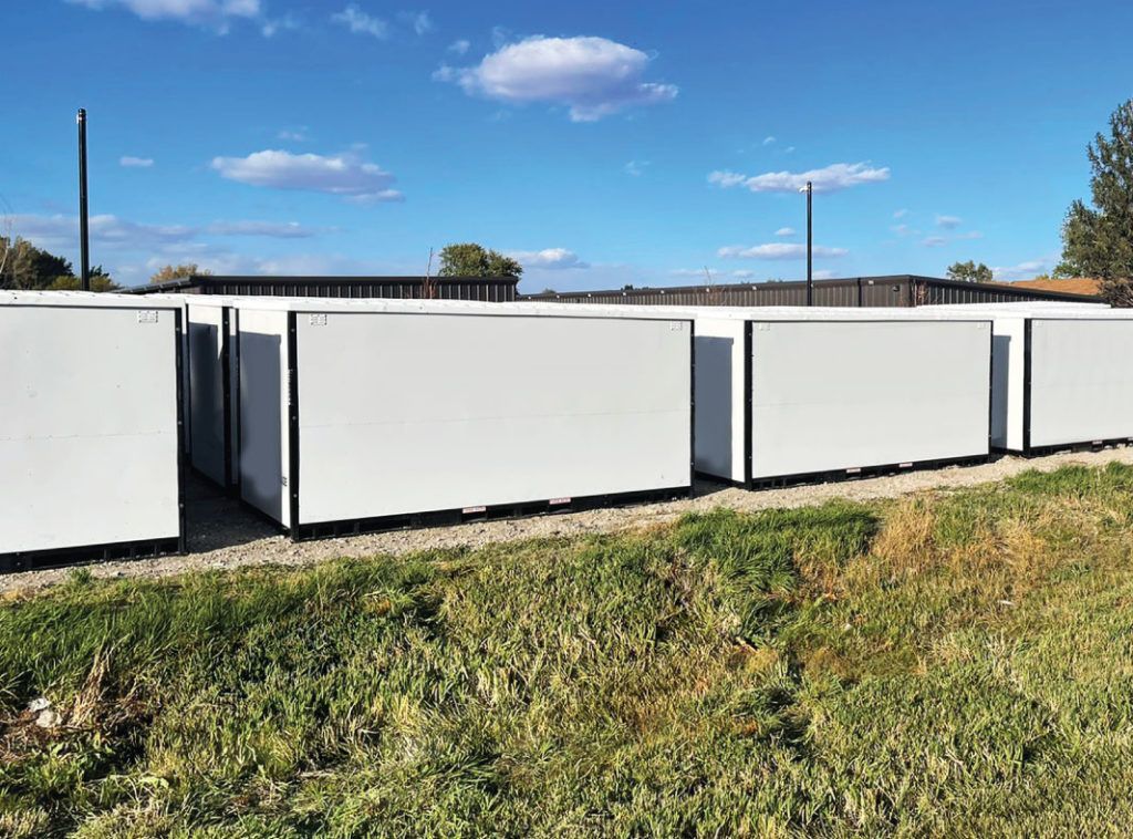 a row of white containers are lined up in a grassy field