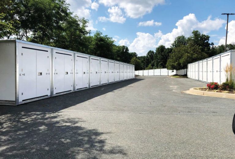 a row of white containers are lined up in a parking lot .