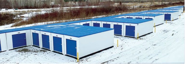 a row of storage units with blue roofs in the snow .