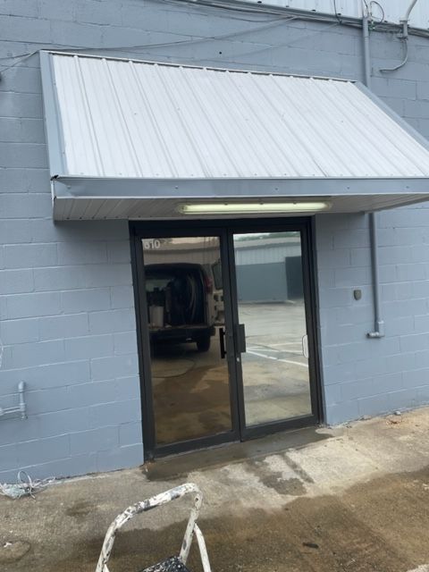 A gray building with a white awning over the door