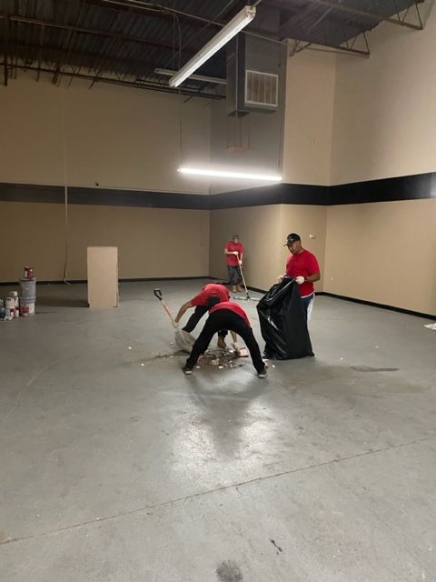 Two men in red shirts are working on a concrete floor