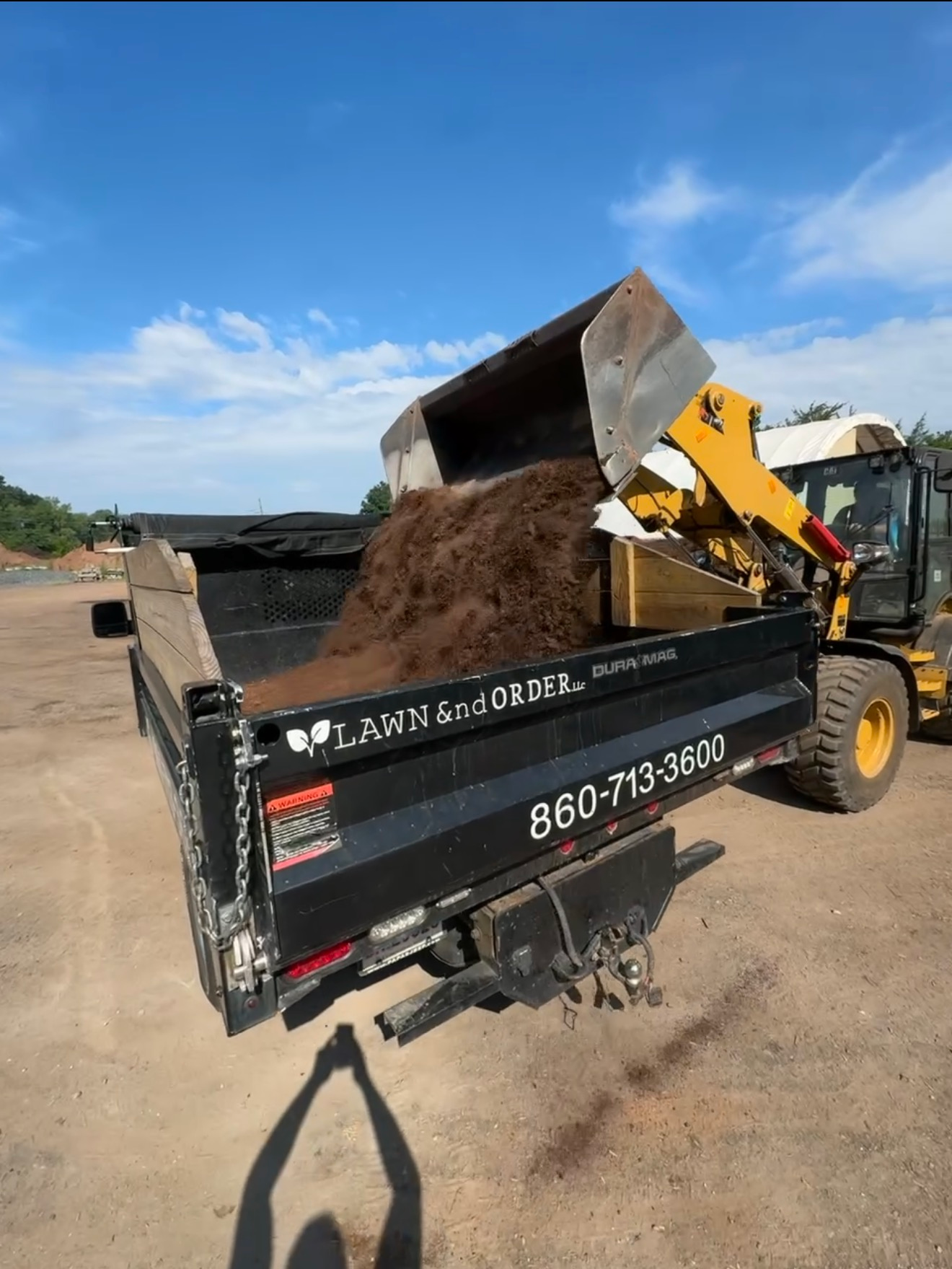 Dumpster filled with dirt at a construction site under a blue sky