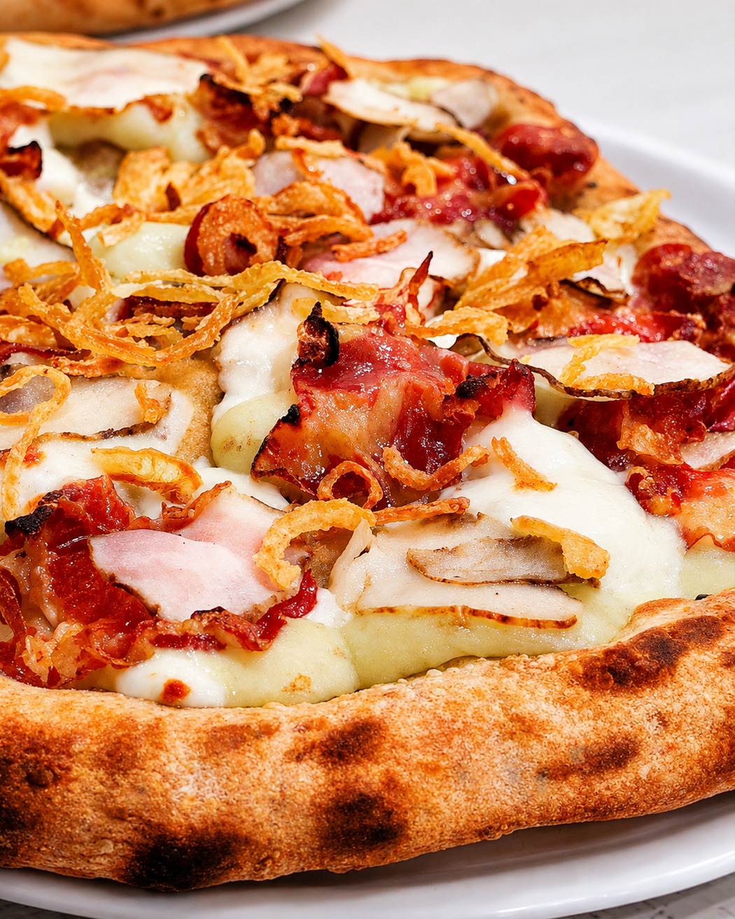 Primo piano di una pizza con peperoni e salsiccia, con formaggio fuso, su un piatto bianco.