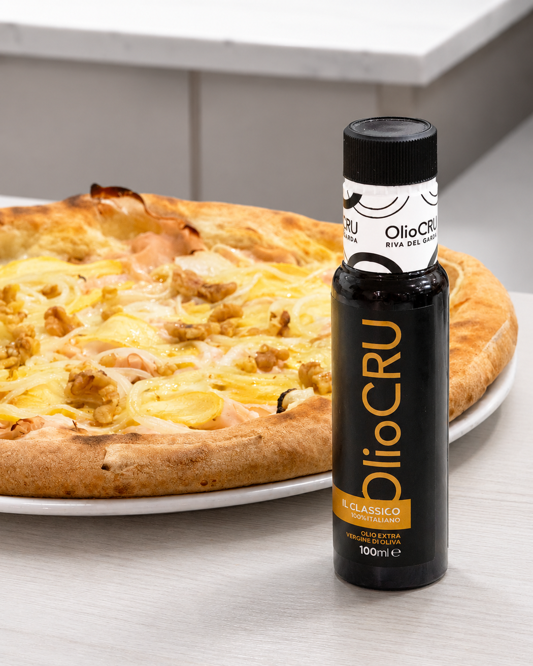 Una bottiglia di olio BioCru su un tavolo accanto a una pizza su un piatto.