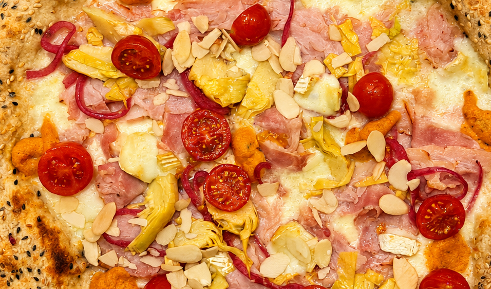Pizza condita con pomodorini, prosciutto, ananas e mandorle a lamelle