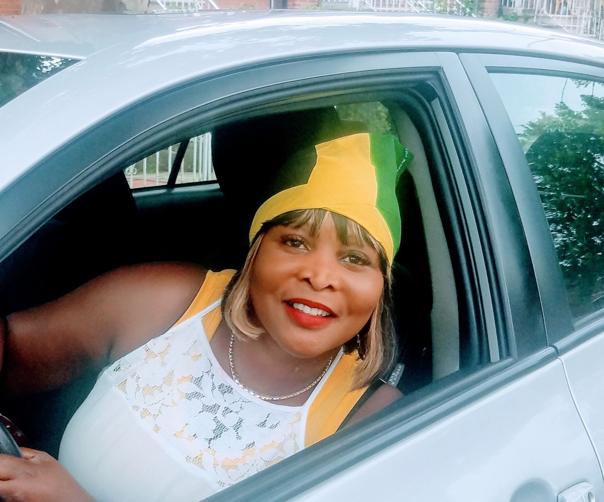 A woman wearing a yellow and green hat is sitting in a car