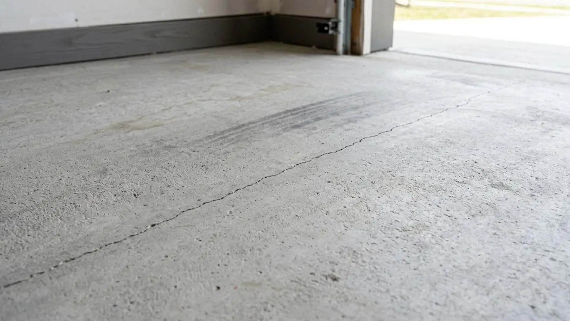 Empty concrete floor in a garage or unfinished room with a doorway on the right