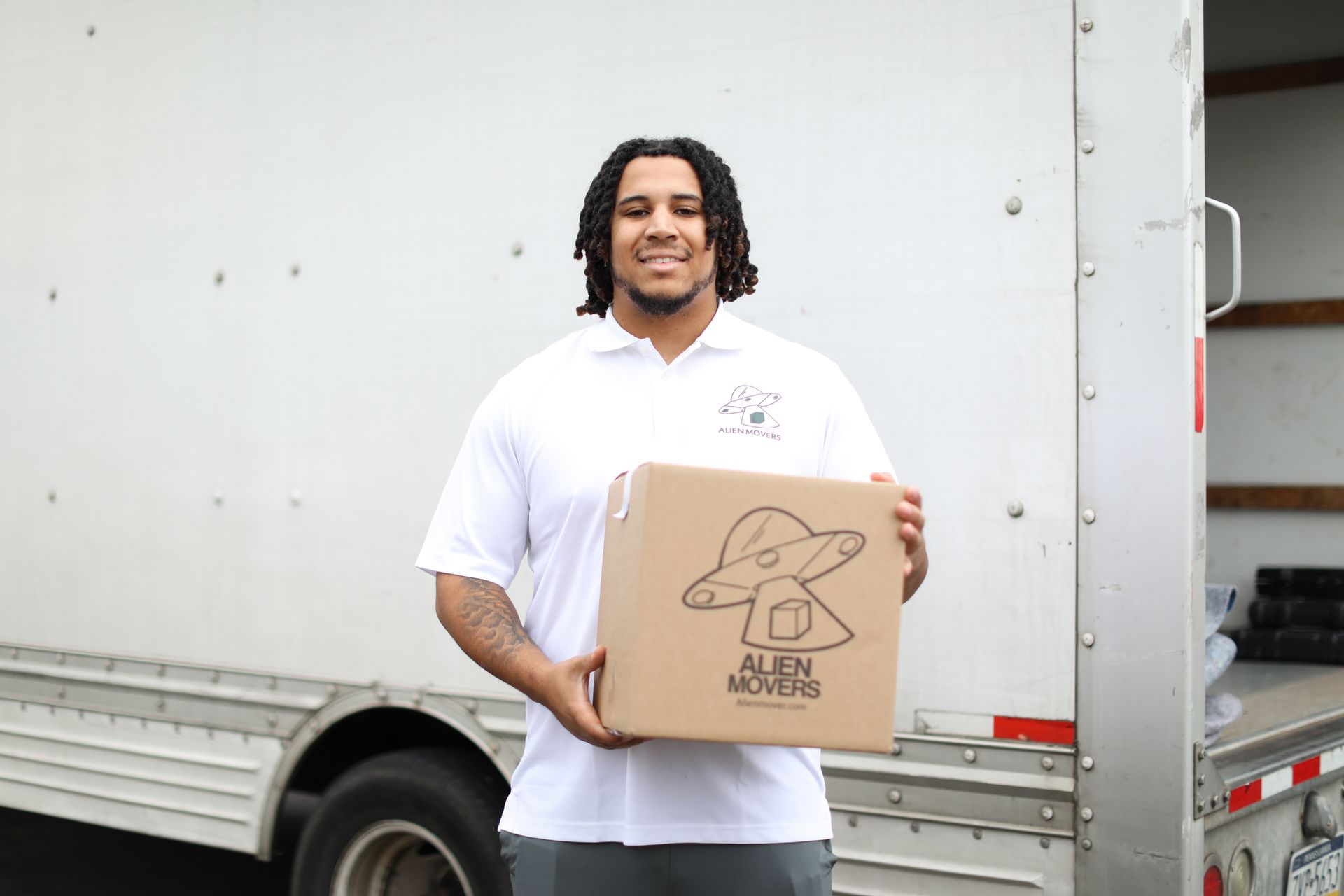 A mover from Alien Movers in an orange shirt encourages calling for a free moving estimate, showcasing the company's customer-focused approach in Philadelphia.
