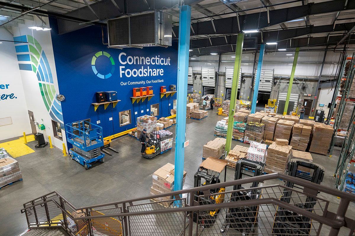 CTFS Warehouse interior with forklifts, pallets of goods, loading docks, and a wall with the 