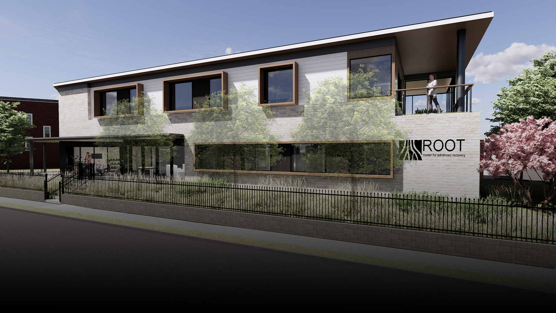 Modern brick building with rooftop deck; Root Center sign; trees, a fence, people.