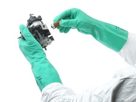 Una persona que lleva guantes verdes sostiene un trozo de metal.