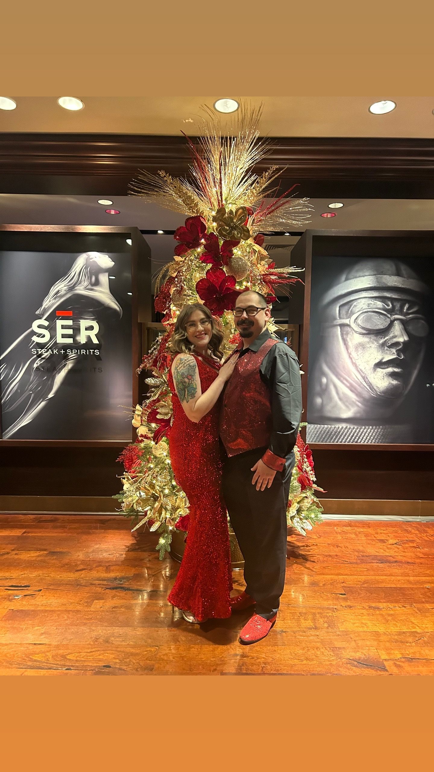 A man and a woman are standing in front of a christmas tree.