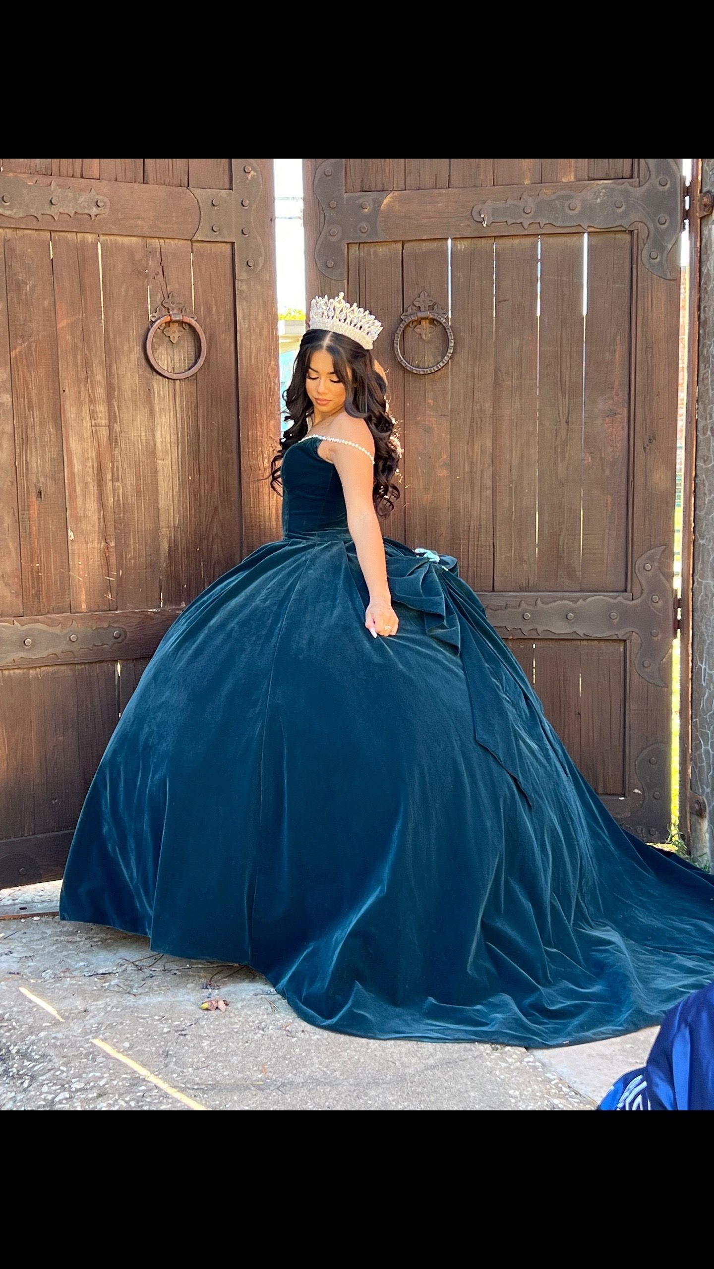 A little girl is wearing a blue ball gown and a crown.