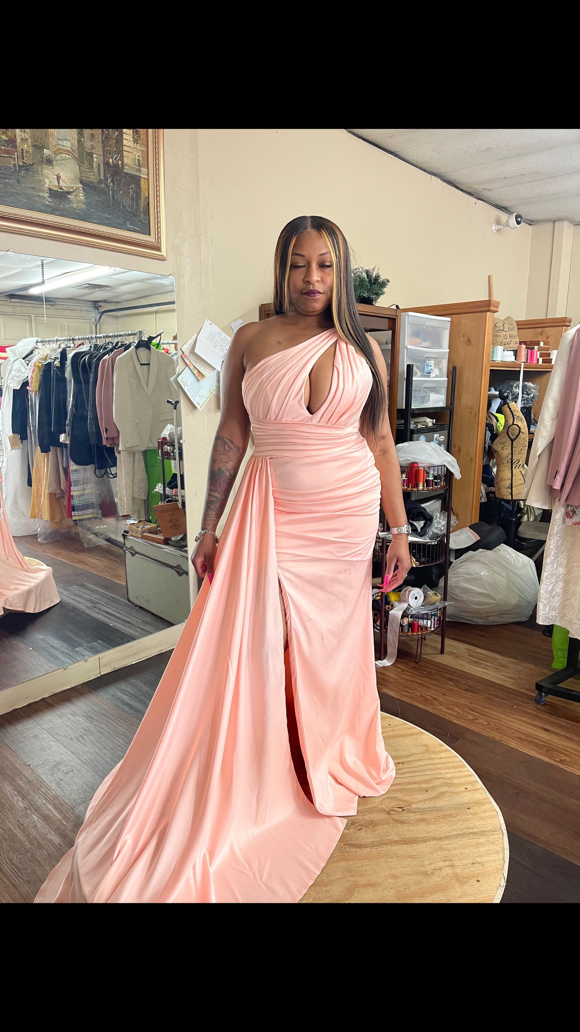 A woman is standing in a room wearing a pink dress.