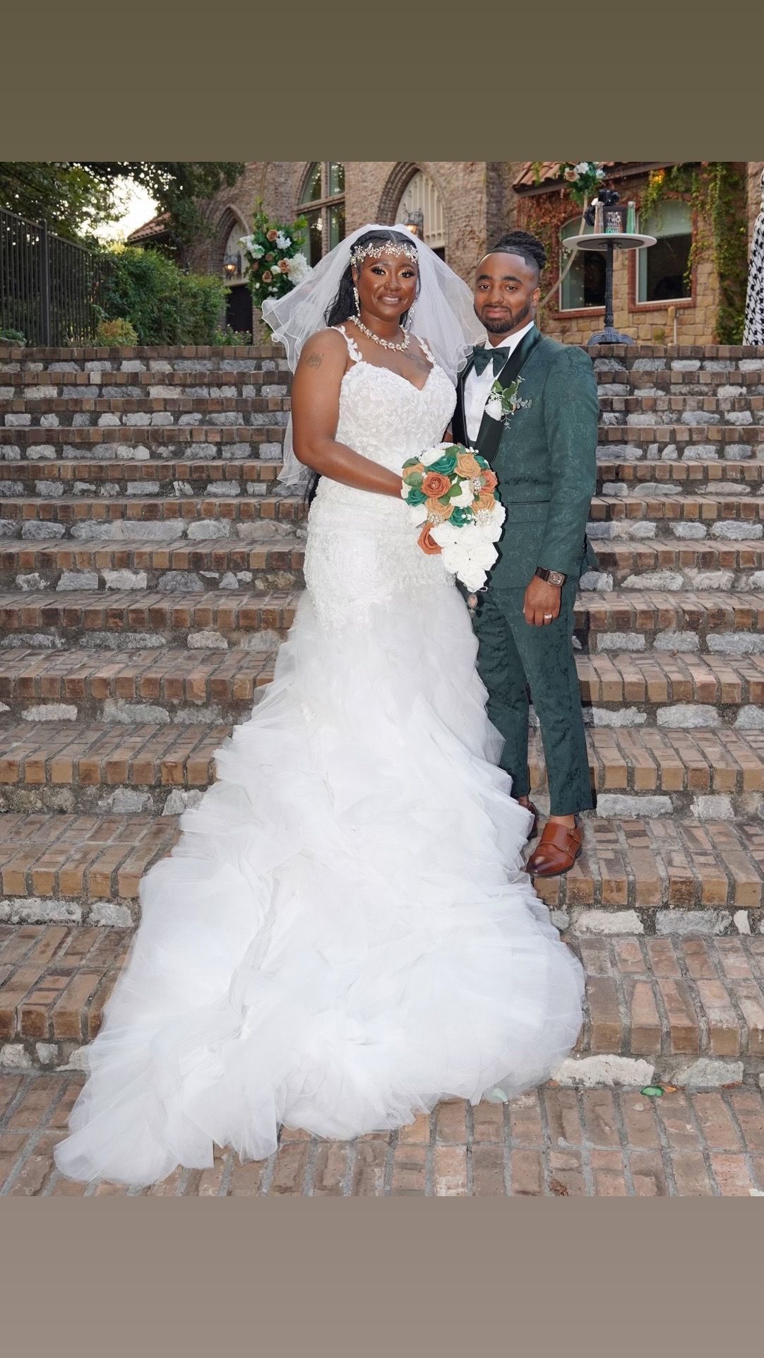 A bride and groom are posing for a picture on a set of stairs.