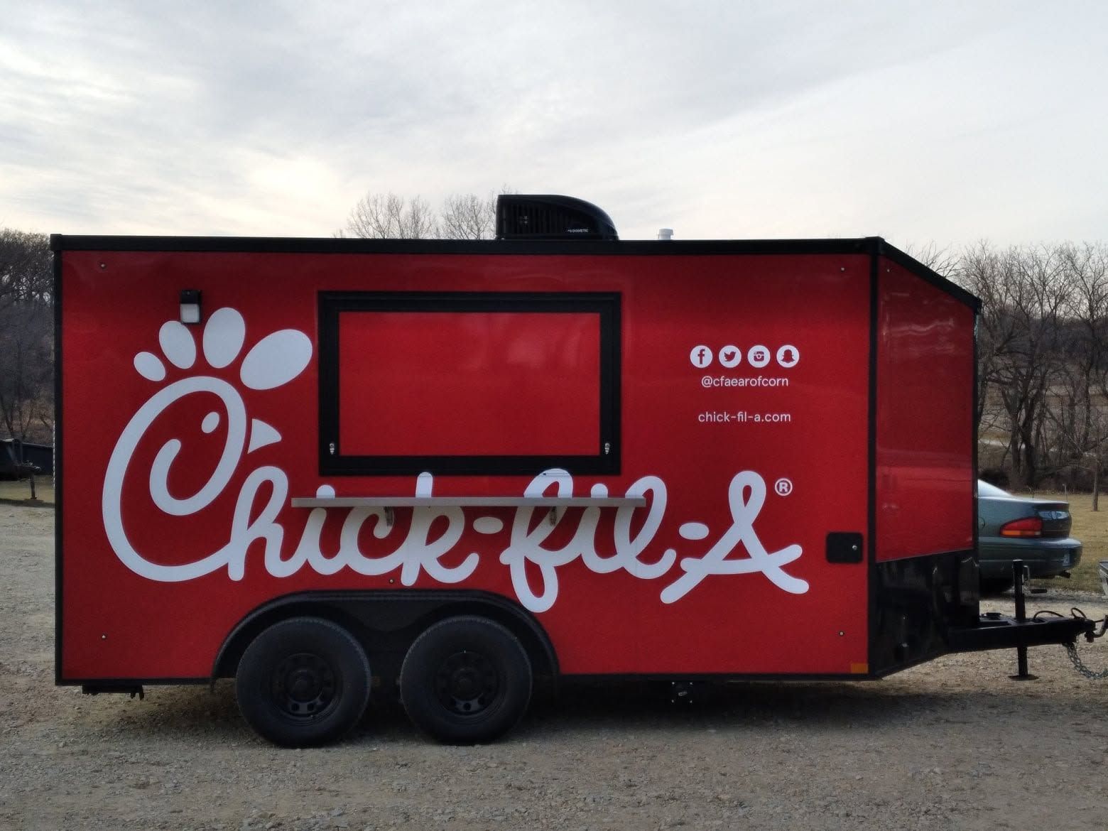 Red Chick-fil-A food trailer with serving window parked outdoors at dusk
