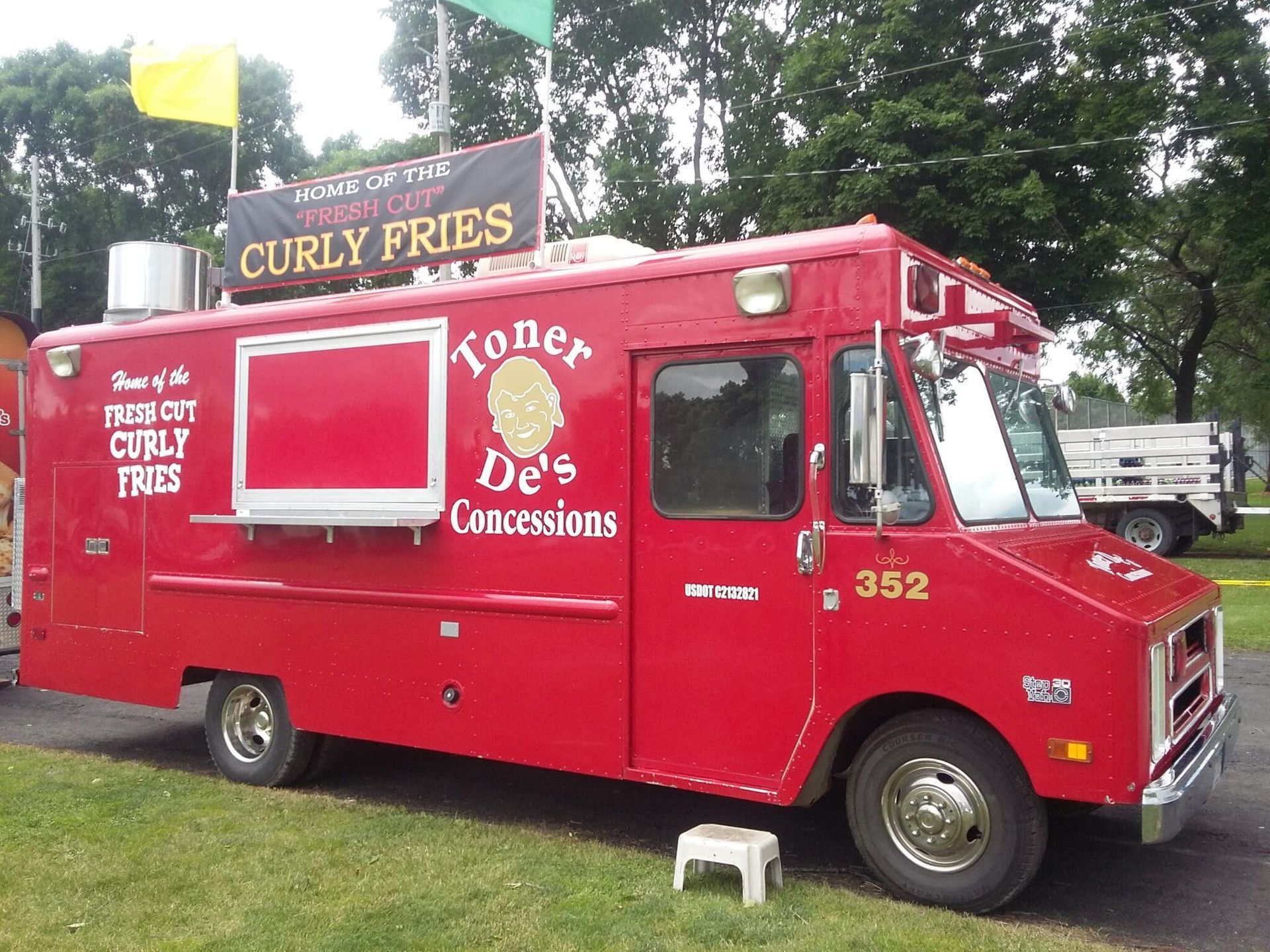 Red hot dog concession food truck parked outdoors with a Curly Fries sign on top