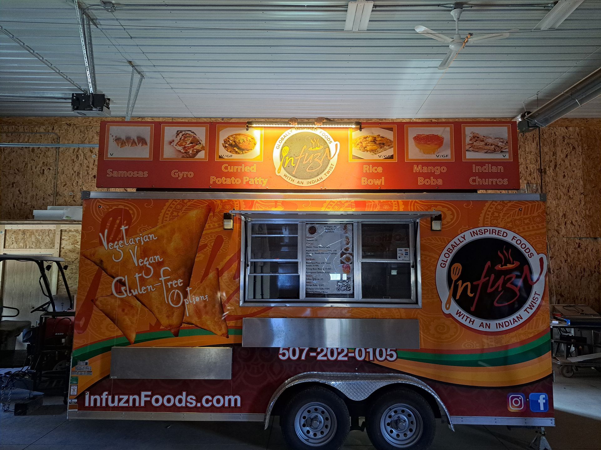 Orange Infuz Foods food truck parked indoors with menu signs and serving window