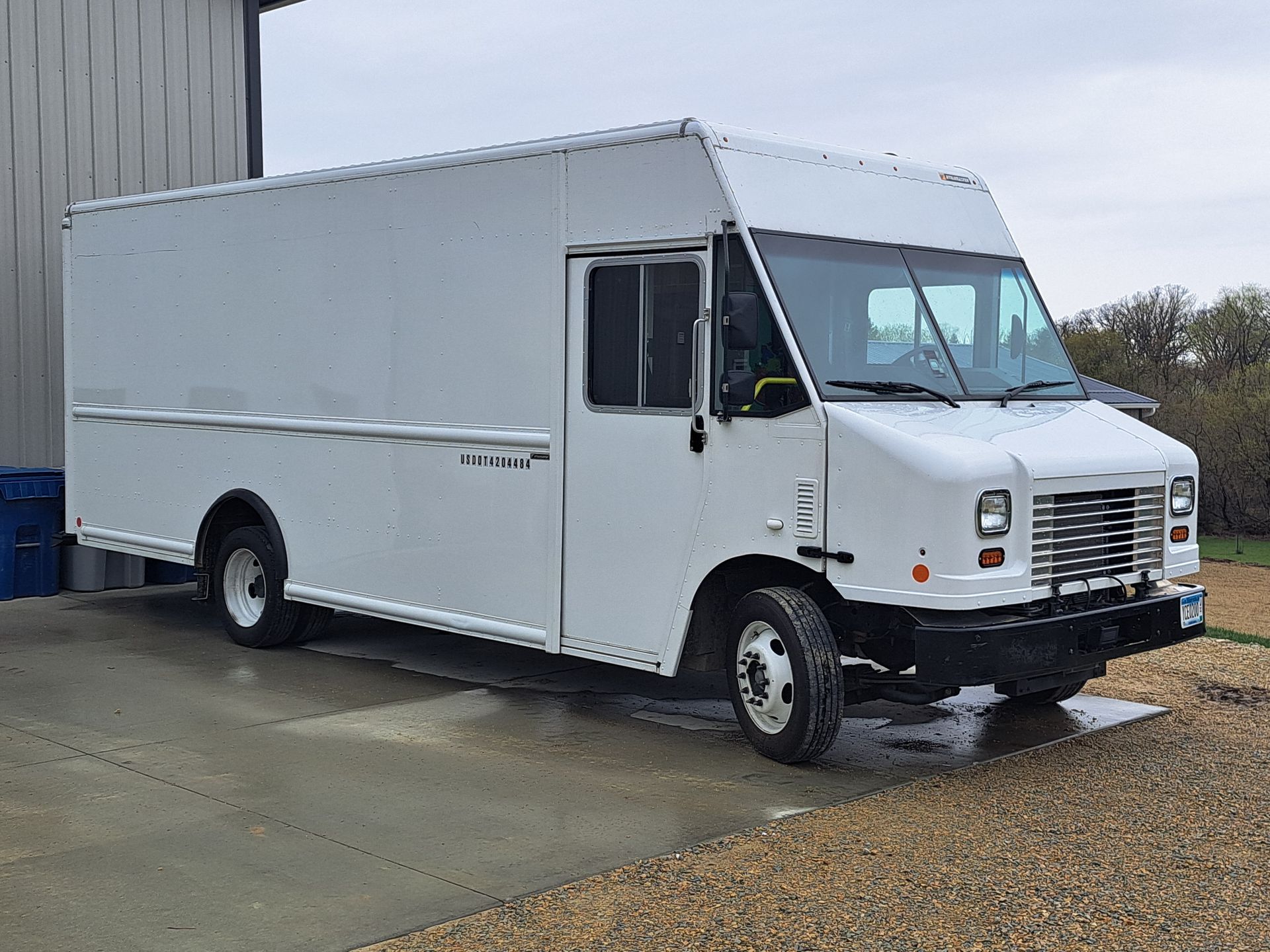 White box truck parked beside a building on a wet lot