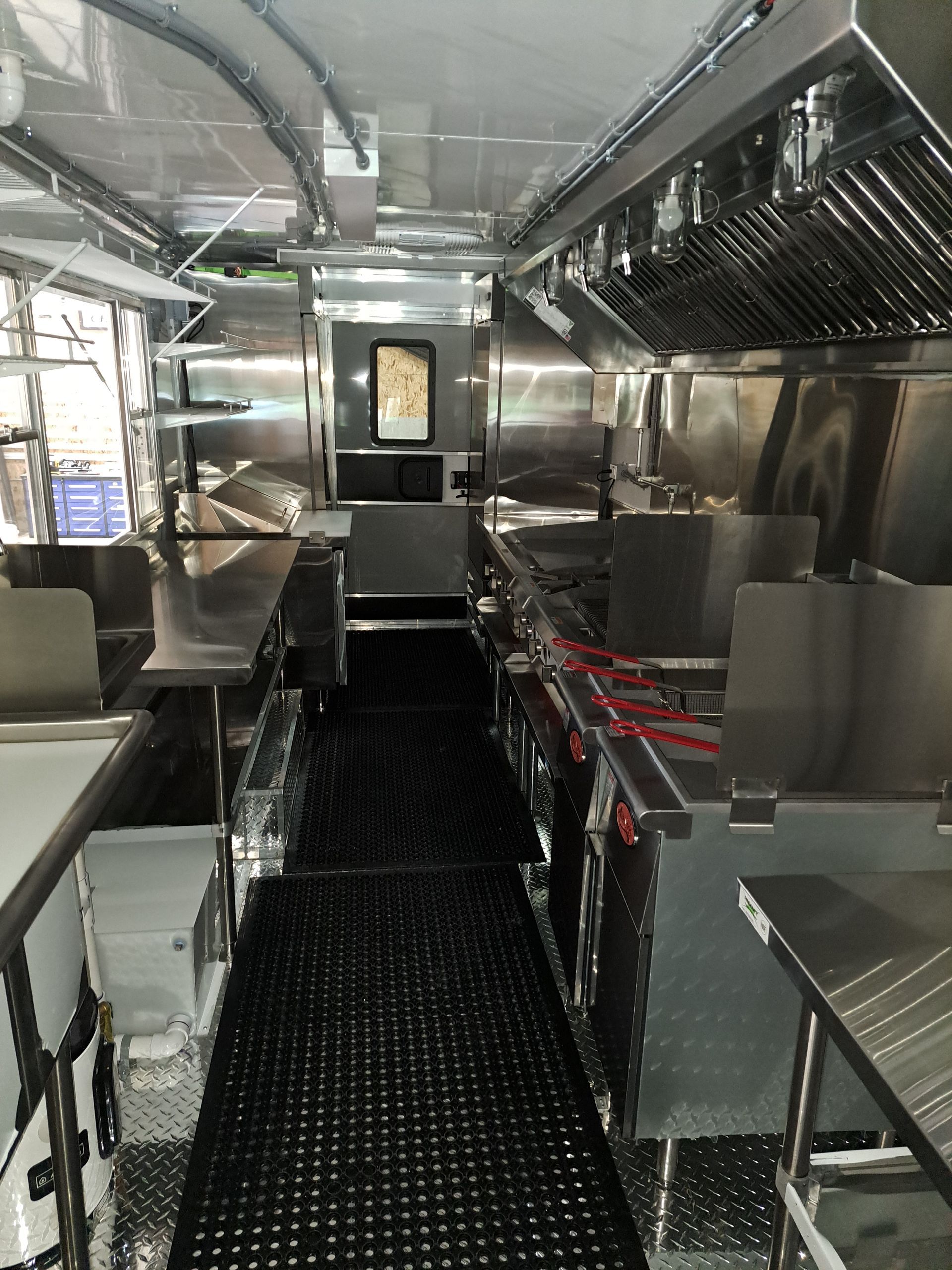 Narrow stainless-steel ship kitchen or galley corridor with countertops and overhead racks