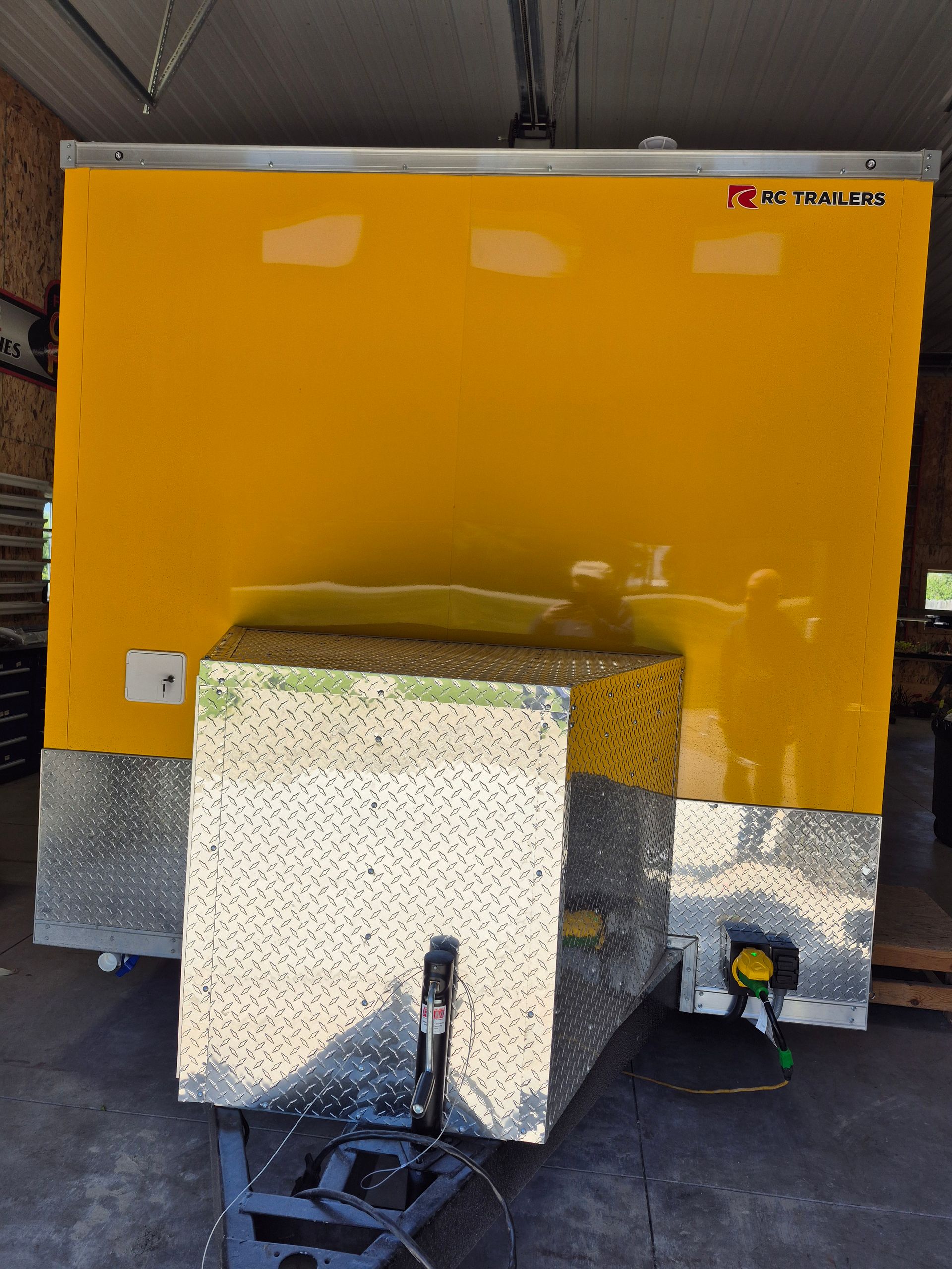Yellow utility trailer with a speckled generator box mounted in front, inside a garage or covered space