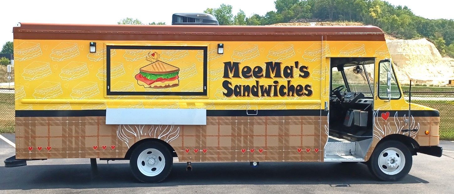 Yellow MeeM’s Sandwiches food truck parked on a street, side view with sandwich logo and awning.