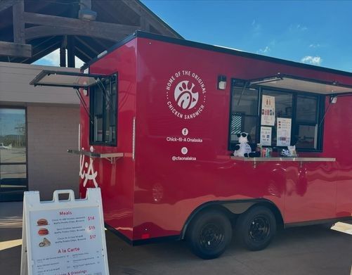Red food trailer serving shaved ice and desserts at a drive-through stand