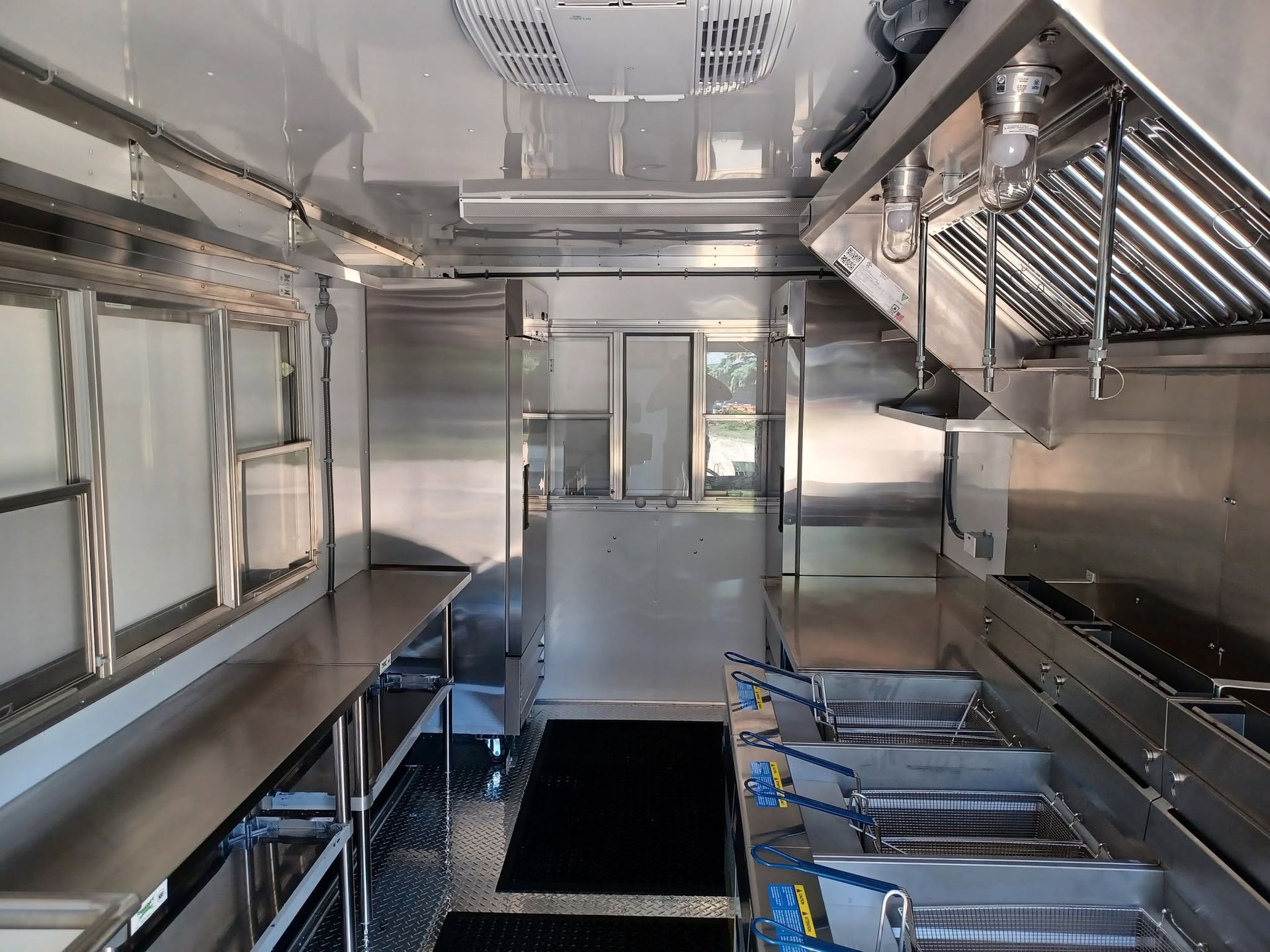 Stainless steel commercial kitchen interior with counters, sinks, and a grill station