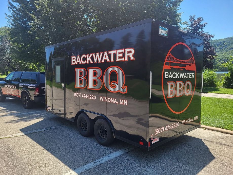 Backwater BBQ food trailer parked outdoors on a sunny day, black with red logo and Minnesota text
