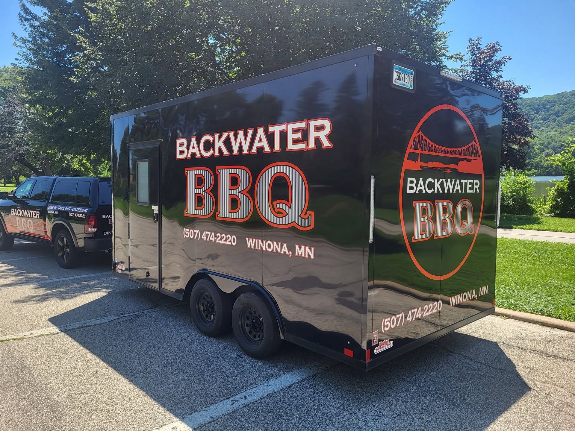 Backwater BBQ food trailer parked outdoors beside a dark pickup truck and trees