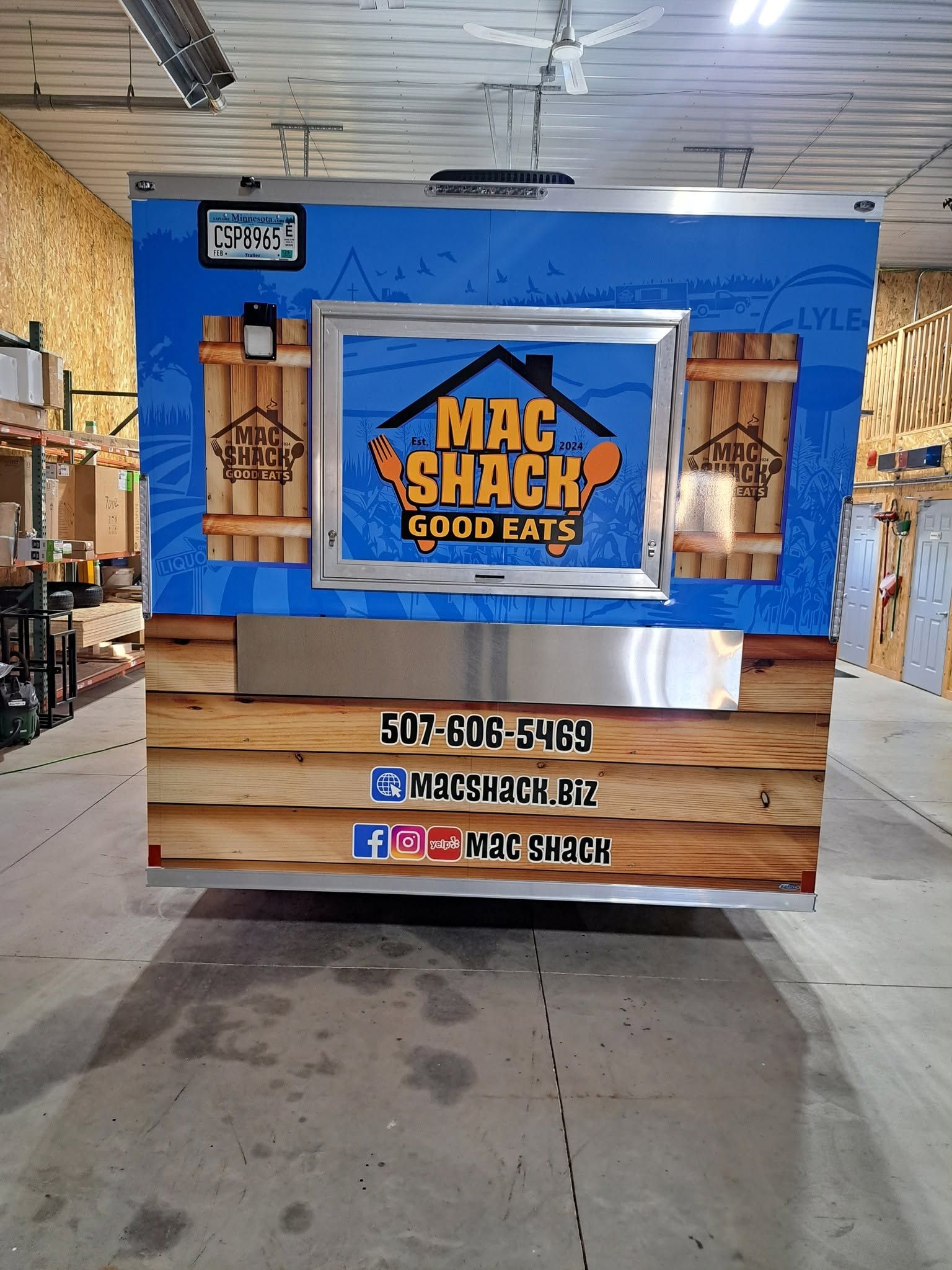 Mac Shack food stand with blue sign and wooden counter at an indoor market booth
