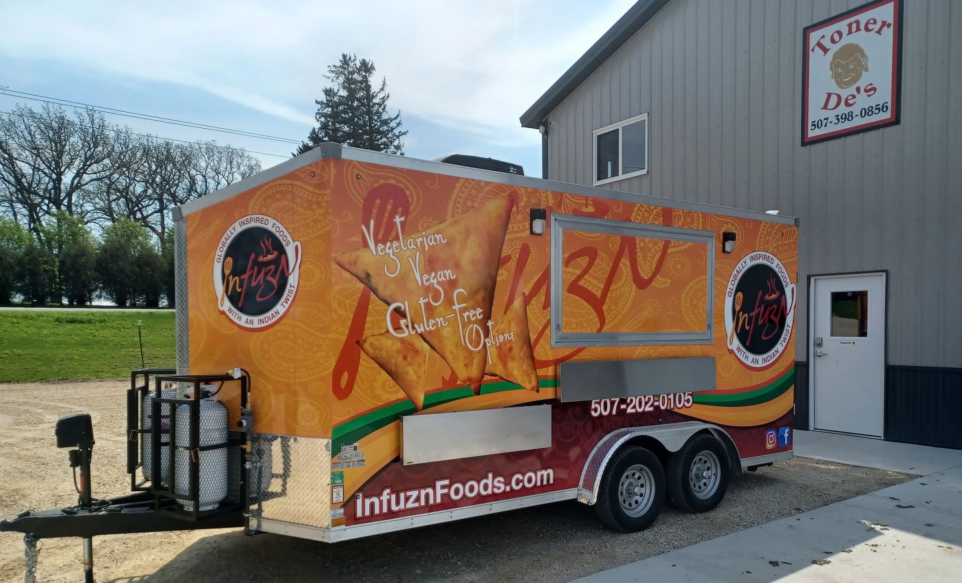 Orange Infuzn Foods food truck parked beside a gray building on a sunny day