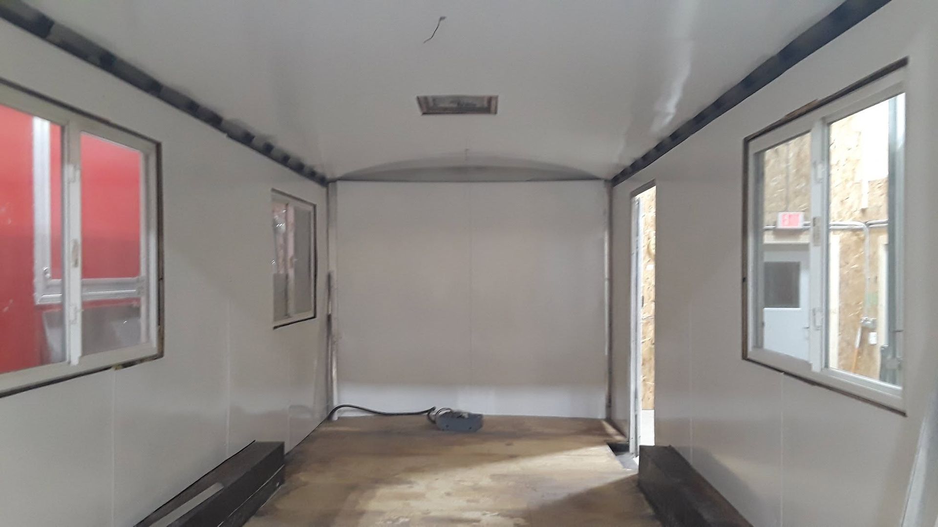 Empty white cargo trailer interior with windows and wooden floor