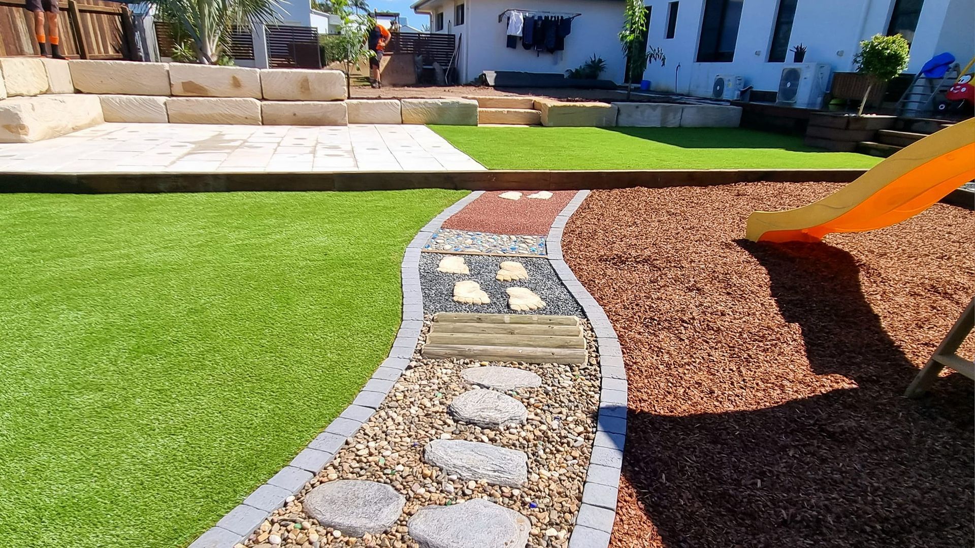 Backyard With Green Lawn, Stone Path, Mulch, and a Playground Slide — On The Mark Landscaping in Branyan, QLD