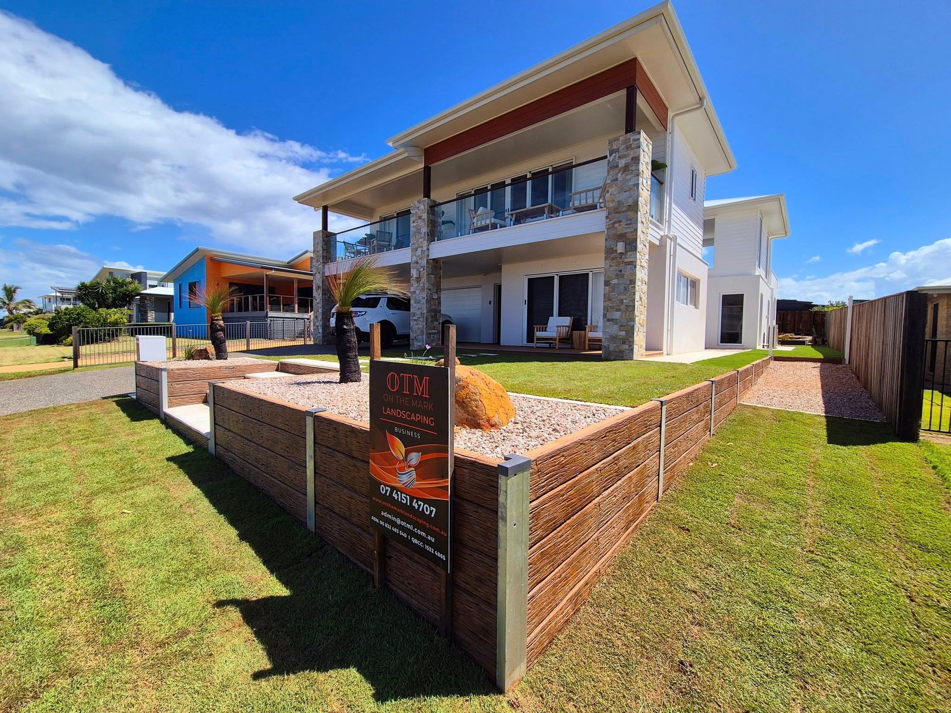 Two-story Modern Home With Stone Accents and a Grassy Yard Under a Blue Sky — On The Mark Landscaping in Branyan, QLD