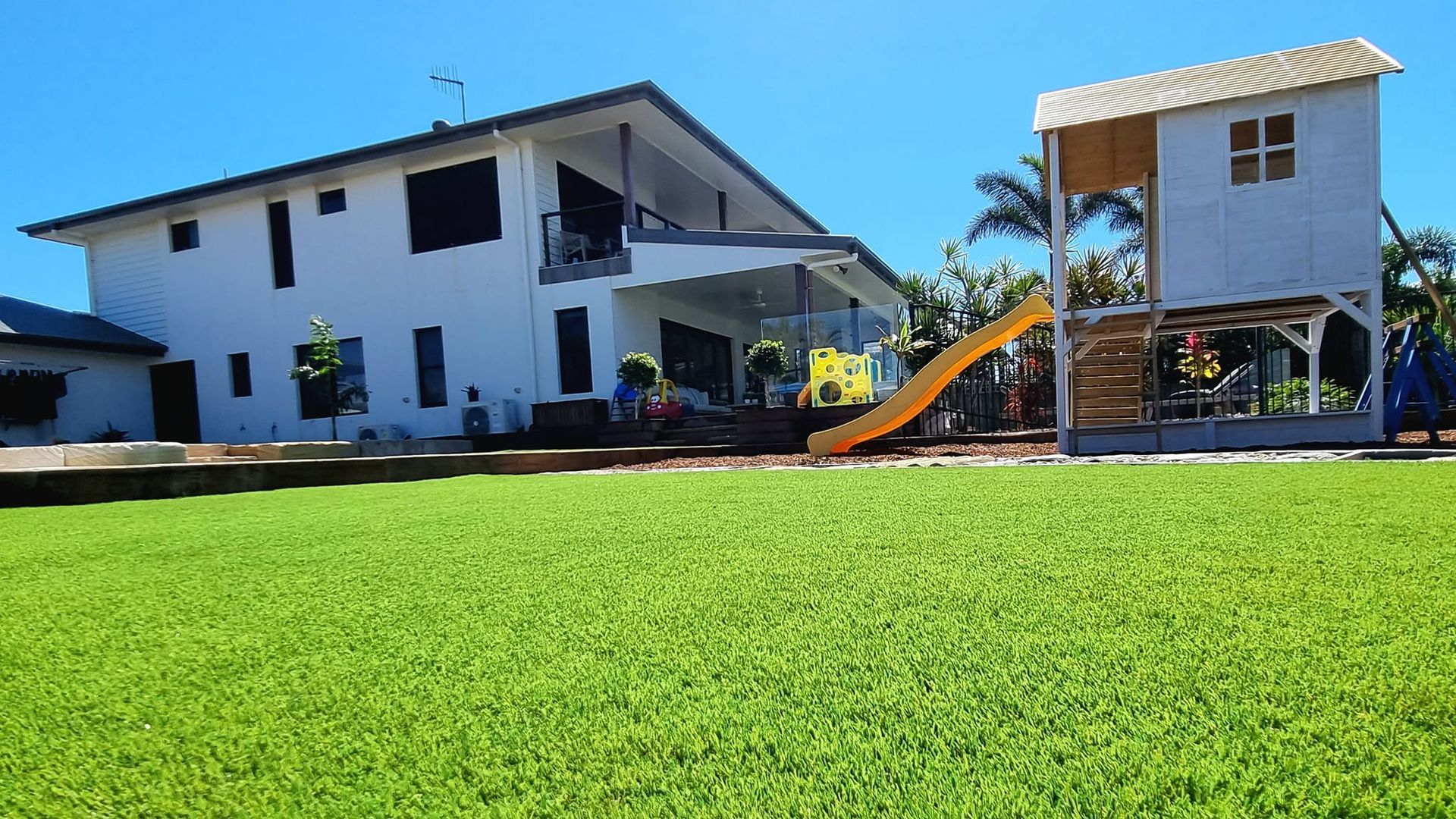 White House With a Playground, Featuring a Slide, on a Green Lawn Under a Blue Sky — On The Mark Landscaping in Branyan, QLD