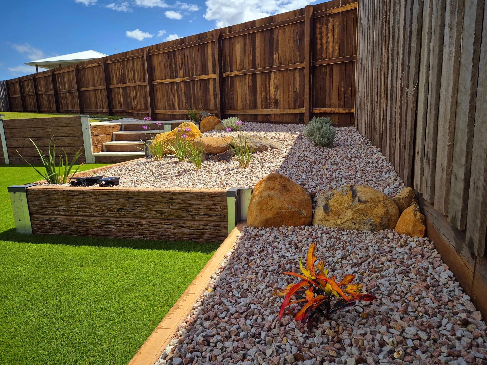 Landscaped Backyard With Gravel, Large Rocks, Plants, and a Wooden Fence — On The Mark Landscaping in Branyan, QLD