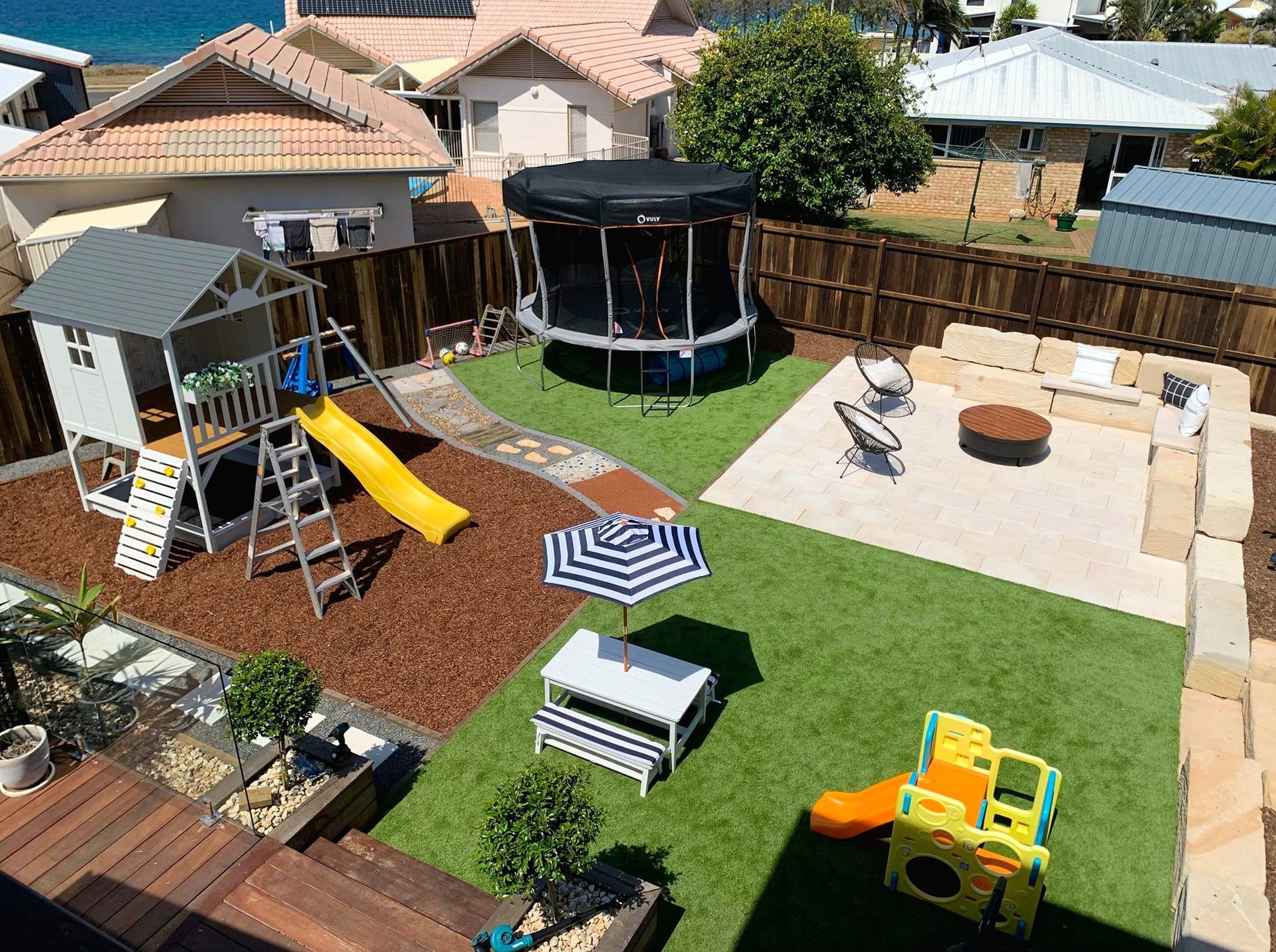 Backyard With Play Area, Trampoline, Patio, and Lounge Seating on Green Grass — On The Mark Landscaping in Branyan, QLD