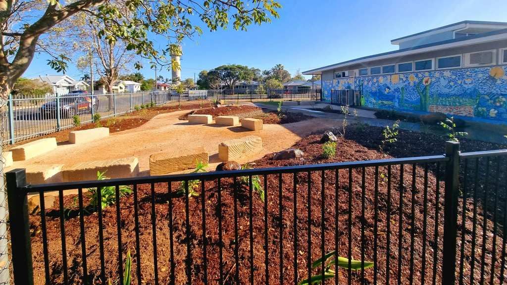 Schoolyard With Mulch, Stone Steps, and Building With Mural Behind a Black Fence — On The Mark Landscaping in Branyan, QLD