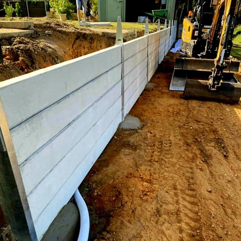 Concrete Retaining Wall Being Constructed Next to an Excavator — On The Mark Landscaping in Branyan, QLD
