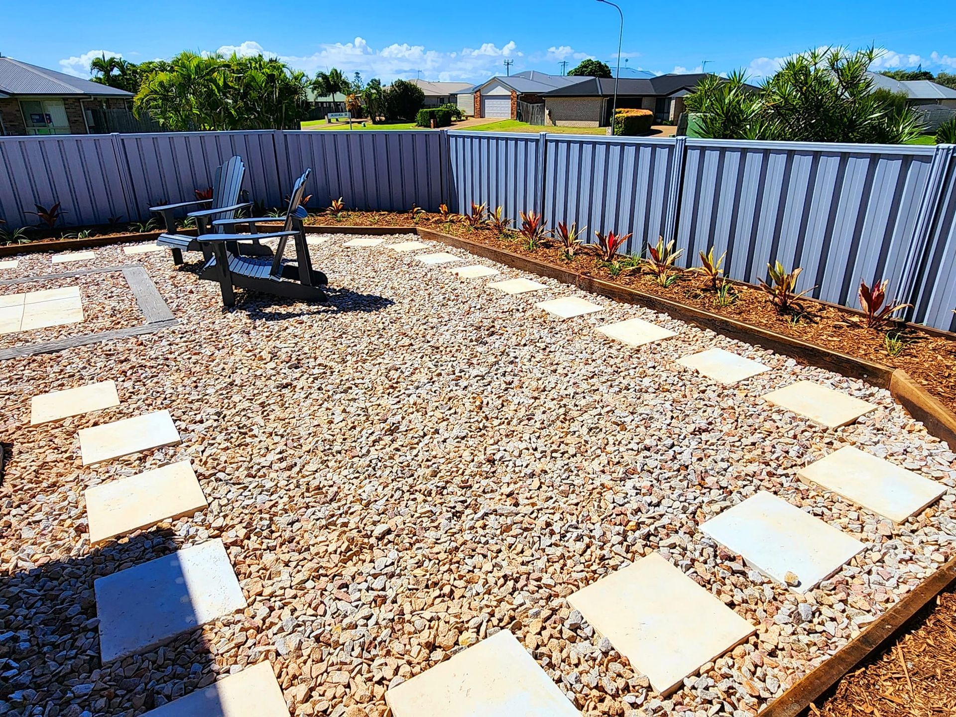 Backyard With Stepping Stones, Wooden Border, and Seating Against a Gray Fence — On The Mark Landscaping in Branyan, QLD