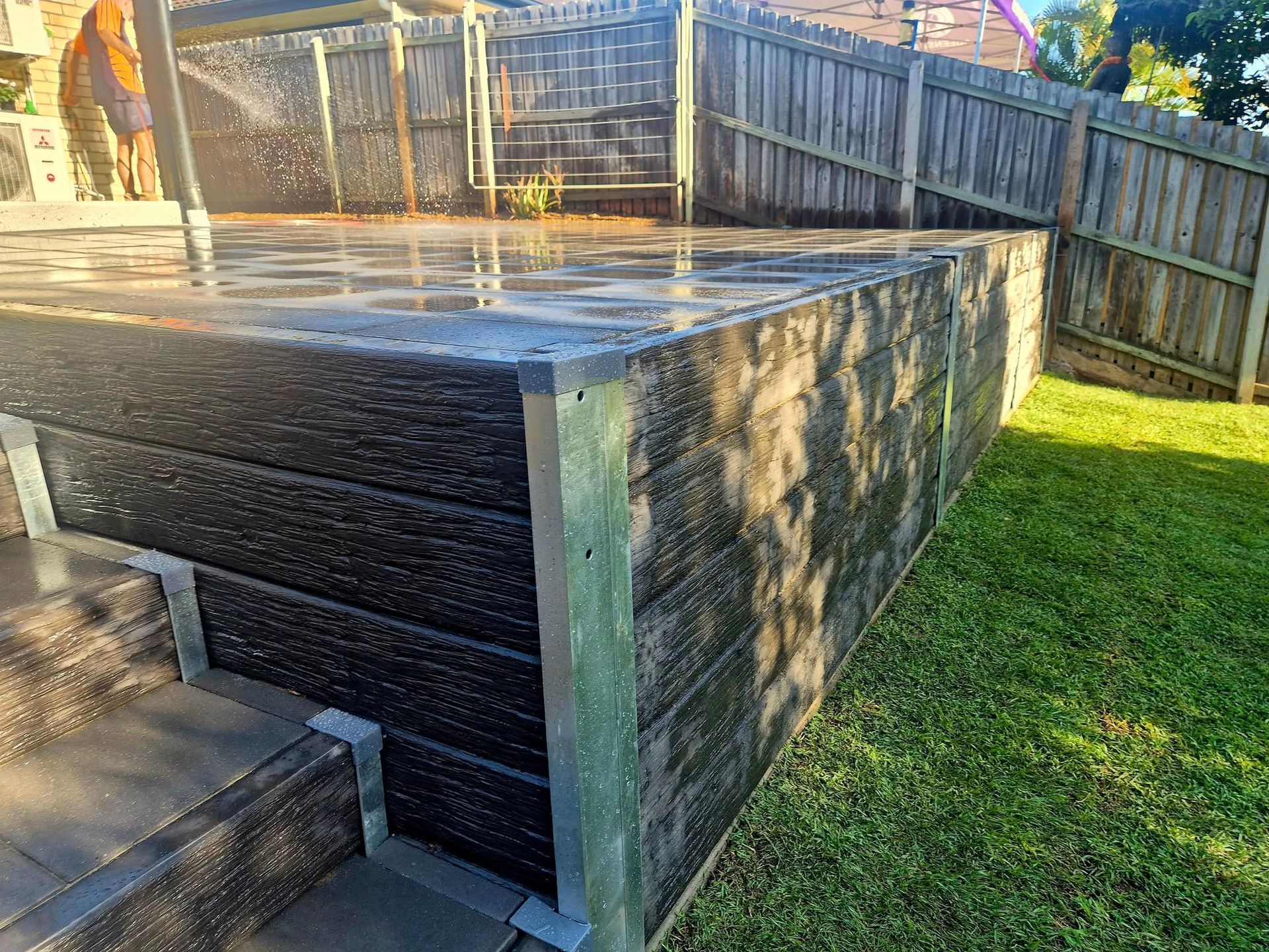 Raised Wooden Deck With Black Planks, Gray Steps, and a Wooden Fence — On The Mark Landscaping in Branyan, QLD