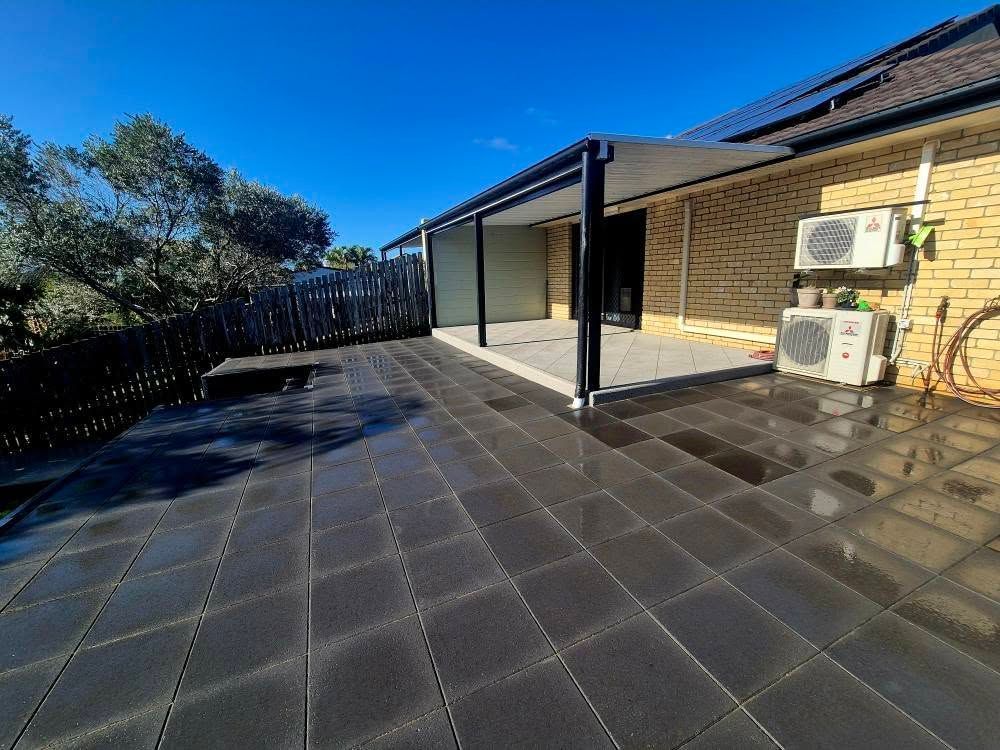 Outdoor Patio With Dark Grey Pavers, Covered by a Black-framed Awning — On The Mark Landscaping in Branyan, QLD
