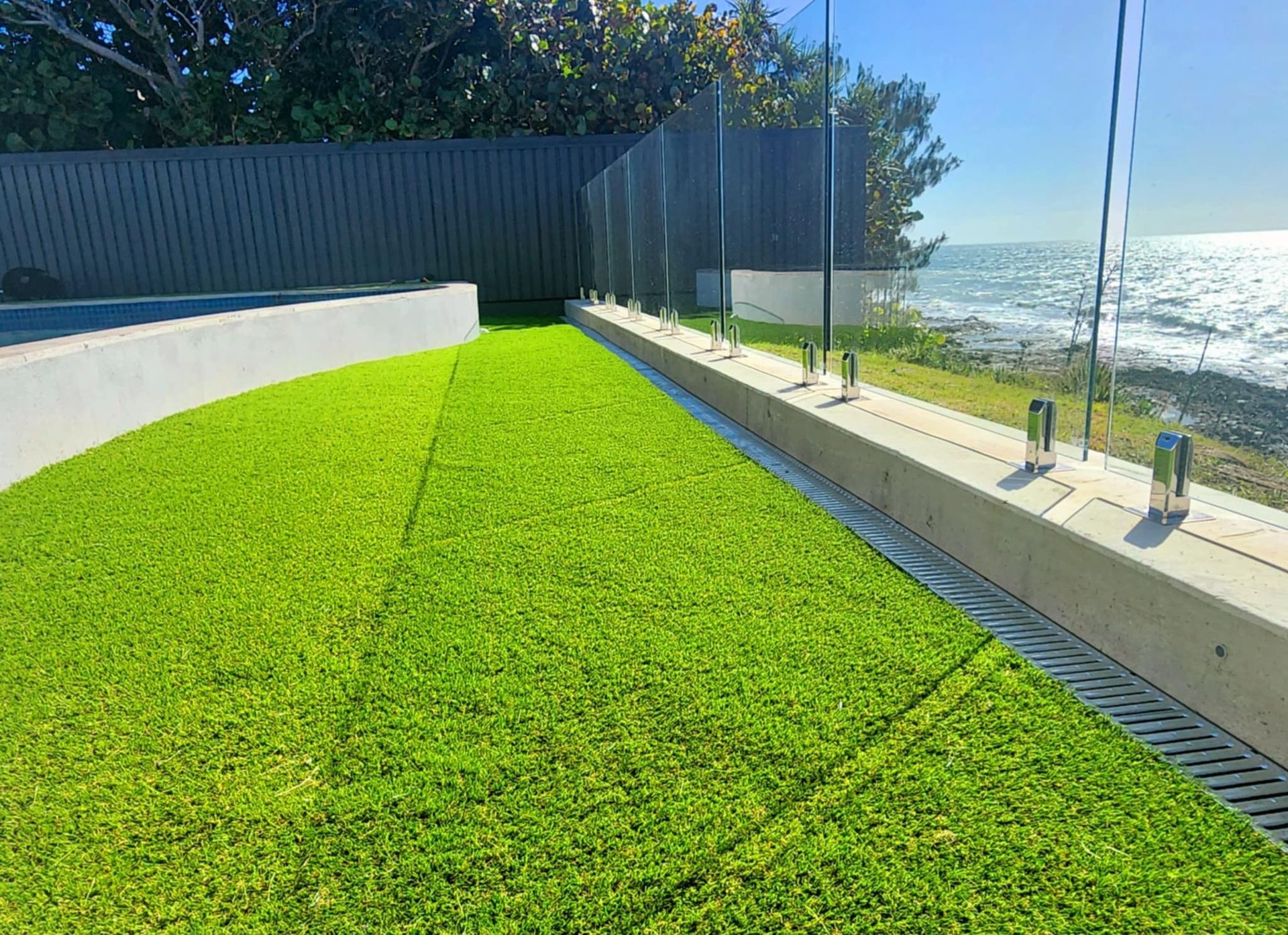 Green Artificial Lawn Next to a Glass Fence, Ocean View — On The Mark Landscaping in Branyan, QLD