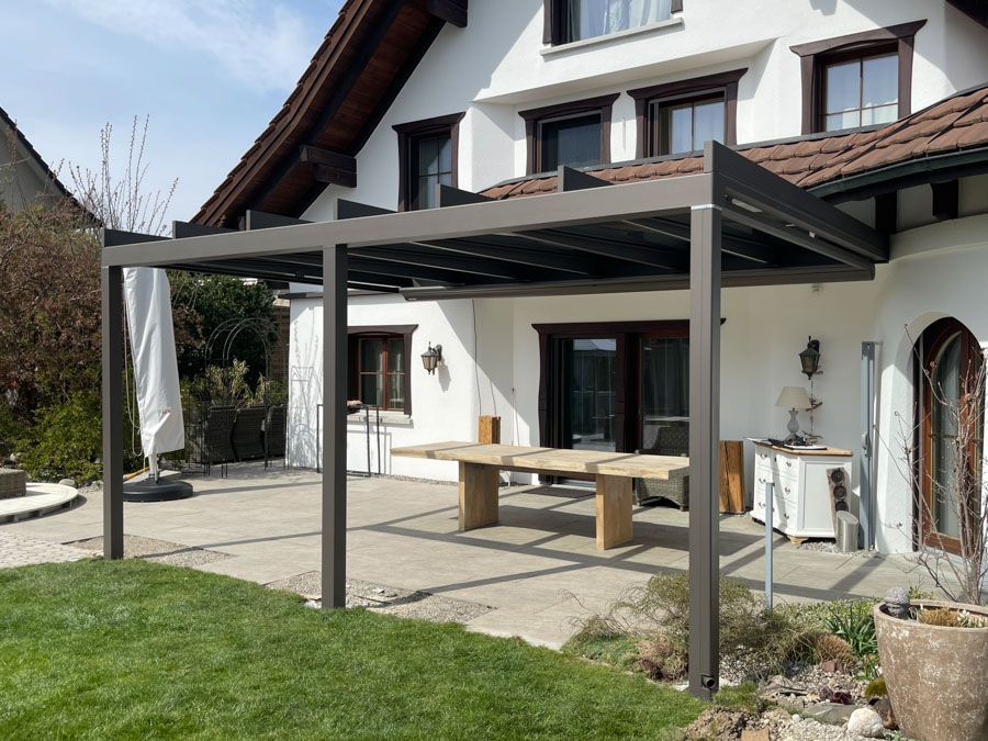 Ein Haus mit einer Pergola und einem Tisch davor