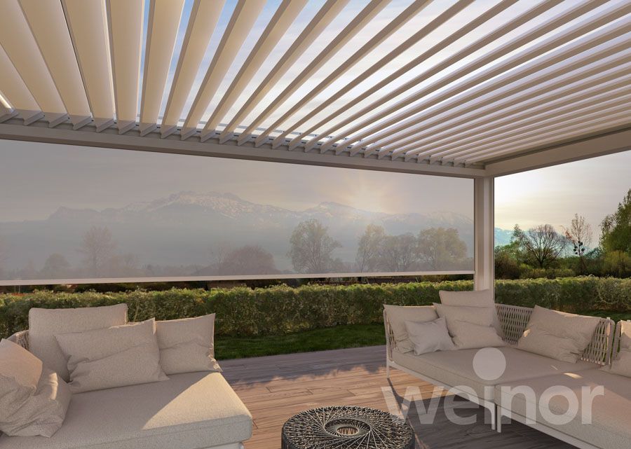 Eine Terrasse mit einer Couch und einem Tisch unter einer Pergola.
