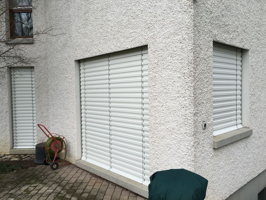 Ein weisses Gebäude mit weissen Jalousien an den Fenstern