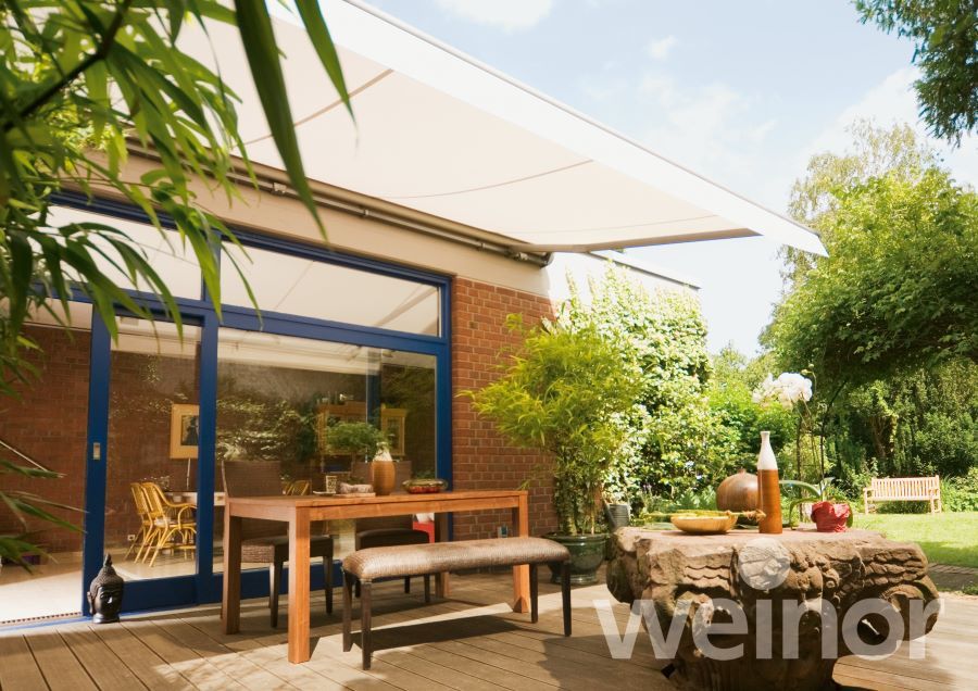 Eine Terrasse mit Tisch und Stühlen unter einer Markise mit der Aufschrift „weinor“