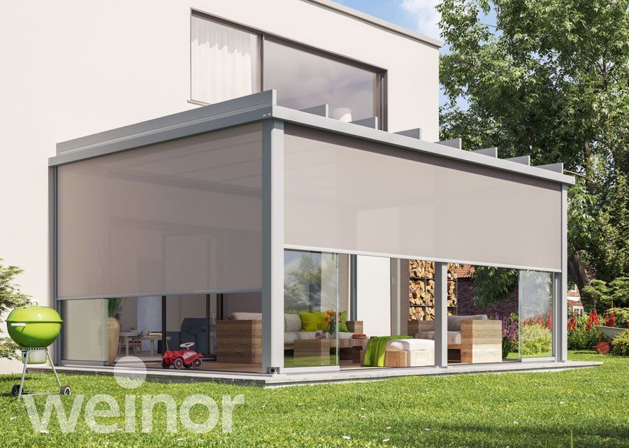 Auf einem üppigen grünen Rasen steht ein Haus mit Pergola und Glasschiebetüren.